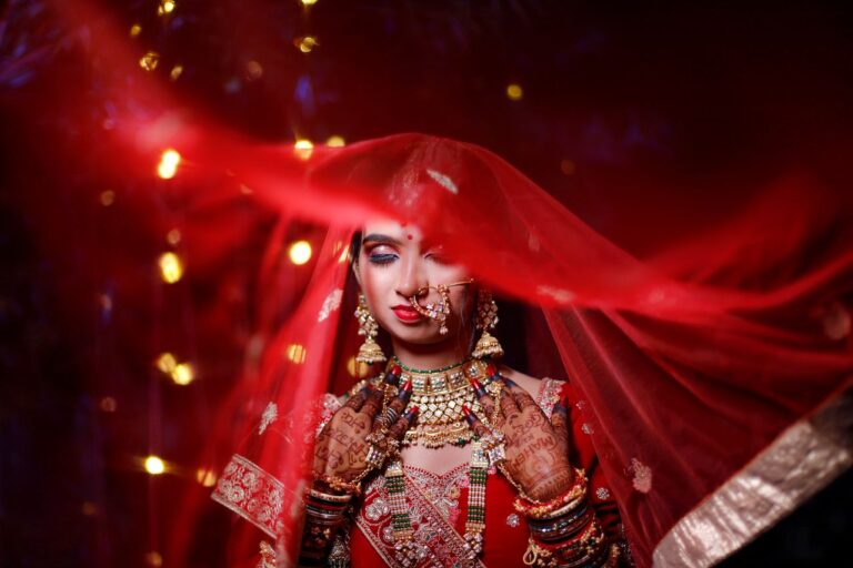 Captivating portrait of an Indian bride in red attire with intricate jewelry and henna, symbolizing cultural elegance.